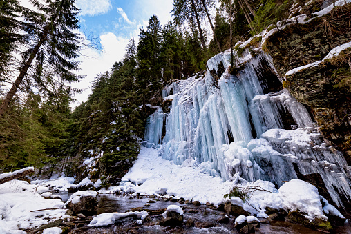 Mountain slopes covered in ice and icicles as the winter snow is melting during cold temperature, forming ice waterfalls along the slopes