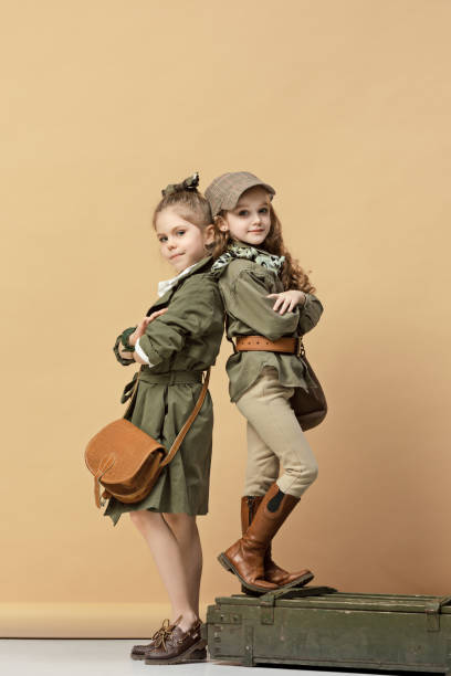 Two beautiful teen girls standing on a pastel studio background. Stylish young teen girls posing at studio. Safari style. Classic style. Teen and kids fashion concept. children's fasion concept
