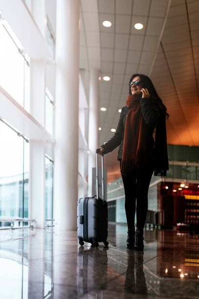 istock Woman walking with suitcase in the airport while using the mobile. 931825304