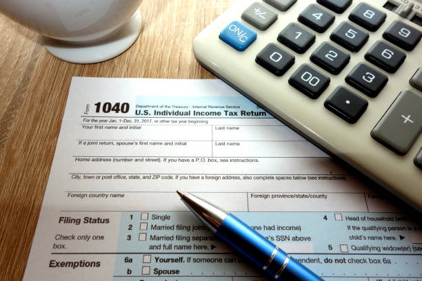 istock US 1040 tax form, calculator and pen on desk 931825458