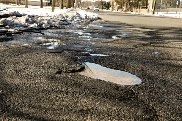 istock Dangerous potholes filled with water in road 931831418