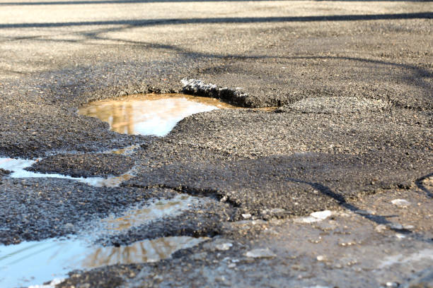 istock Large Pothole filled with water in road 931831470