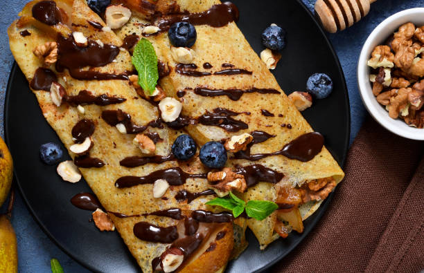 istock Homemade thin pancakes with caramelized pears, chocolate sauce and nuts on a concrete background. 931834228