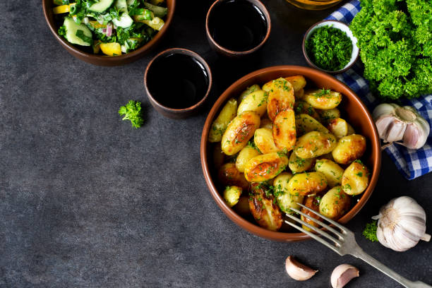 Young fried potatoes with garlic and dill on a black background stock photo