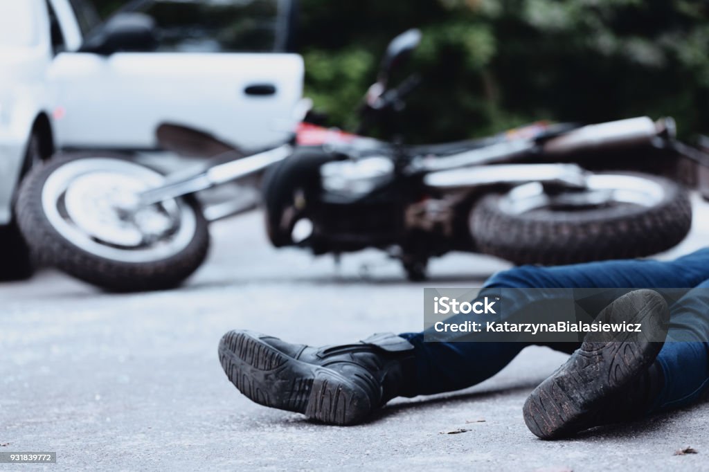 Victim of motorbike accident Victim of a motorbike accident lying on the street unconscious Crash Stock Photo