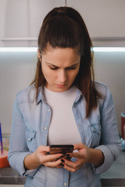 istock Angry girl looking at mobile phone in the kitchen 931841144