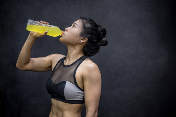 Young Asian athlete woman drinking sport drink or energy drink after exercise Young Asian athlete woman drinking sport drink or energy drink after exercise in fitness gym, healthy lifestyle concepts sport drink stock pictures, royalty-free photos & images