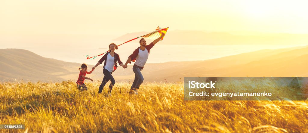 Happy family father,  mother and child daughter launch a kite on nature at sunset Family Stock Photo