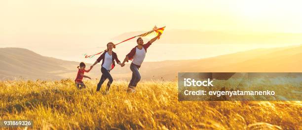 Happy Family Father Mother And Child Daughter Launch A Kite On Nature At Sunset Stock Photo - Download Image Now