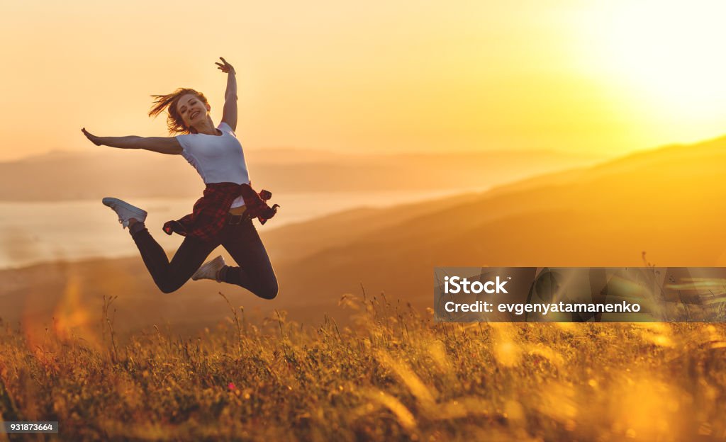 Happy woman jumping and enjoying life  at sunset in mountains Happy woman jumping and enjoying life in field at sunset in mountains Vitality Stock Photo
