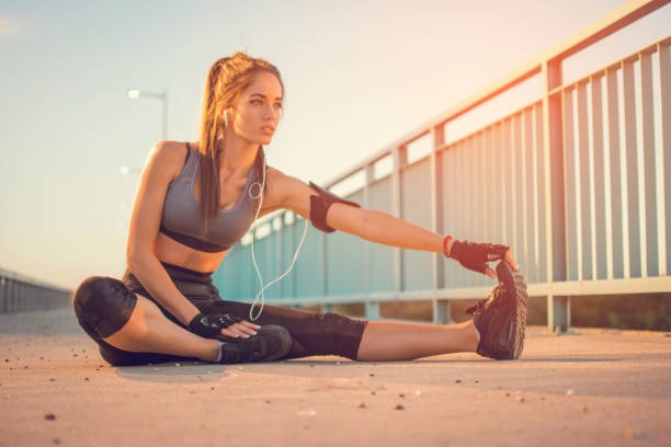 Young sportswoman stretching and touching her toes with her hand outdoors. Sporty girl stretching on the bridge. Young sportswoman stretching and touching her toes with her hand outdoors. Sporty girl stretching on the bridge. touching toes stock pictures, royalty-free photos & images