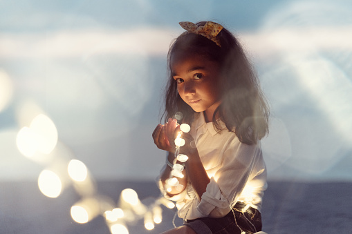 Child holding fairy lights and looking at camera