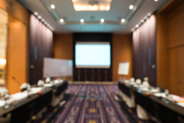 istock Blurred, defocused background of modern conference room with white projection screen. Company meeting, convention center, or business shareholder event concept 931887298