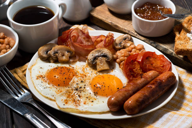 istock Fried eggs with bacon, sausages and vegetables for breakfast, closeup 931889206