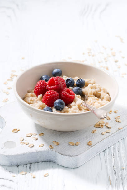 istock homemade oatmeal with berries on white wooden table, vertical 931896606