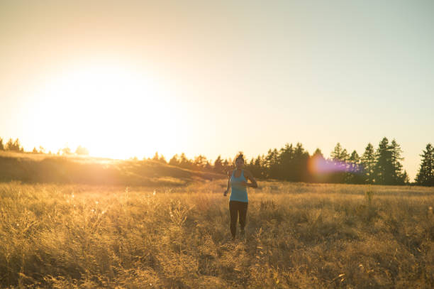 istock Solo female jogger runs through a grass field at dusk 931896878