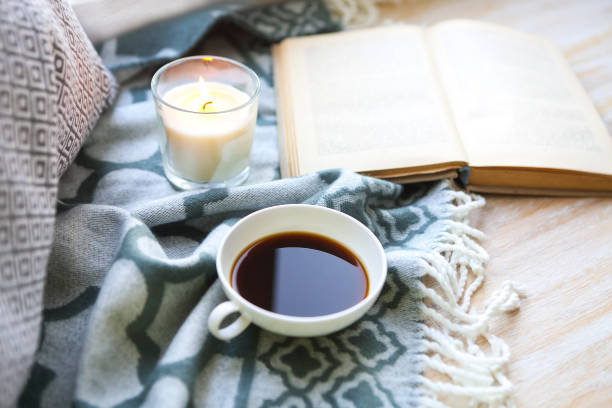 istock Cup of coffee, candle and book on the floor 931901328