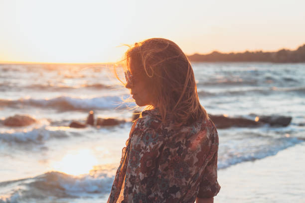 istock Young woman enjoying sunset and waves at the beach 931902416