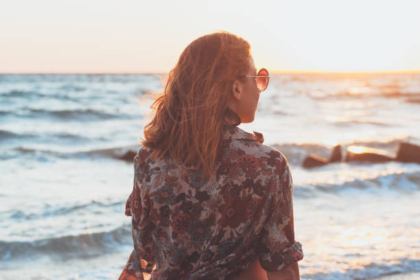 istock Young woman enjoying sunset and waves at the beach 931902424