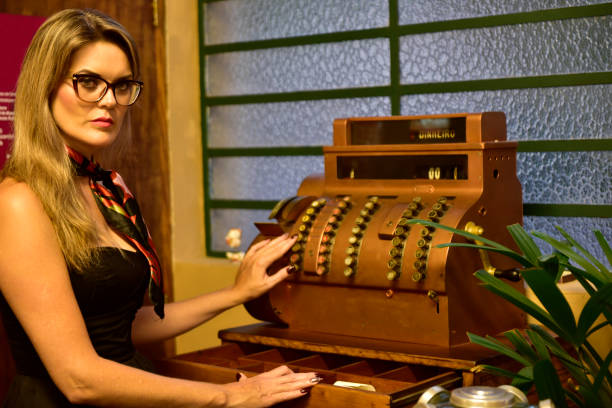 Blonde woman with a vintage look next to an old gold cash register