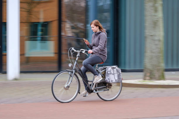 girl riding a bike and looks at her smartphone, danger - child bicycle cycling danger imagens e fotografias de stock