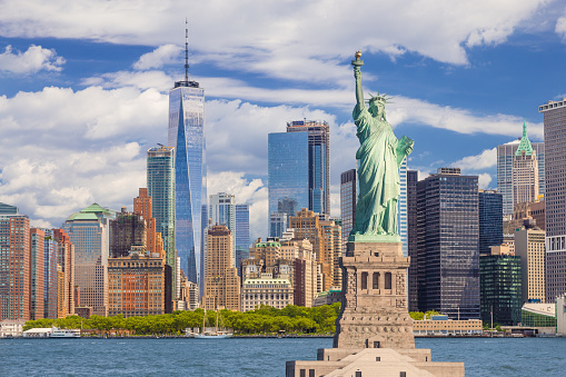 Estatua de la libertad y el horizonte de la ciudad de Nueva York con el distrito financiero de Manhattan, World Trade Center, aguas del puerto de Nueva York, Battery Park y cielo azul. photo