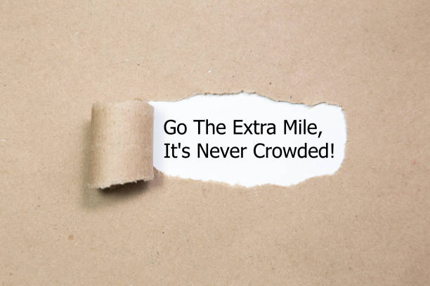 Motivational quote Go The Extra Mile It's Never Crowded appearing behind ripped paper. Motivational quote Go The Extra Mile It's Never Crowded appearing behind ripped paper. commits stock pictures, royalty-free photos & images