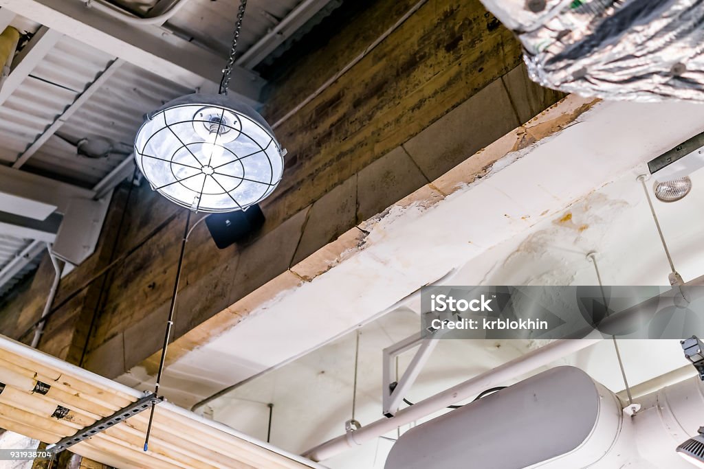 Industrial lamp up hanging on ceiling in warehouse, grunge old building interior closeup, metal pipes, concrete Chelsea - New York Stock Photo