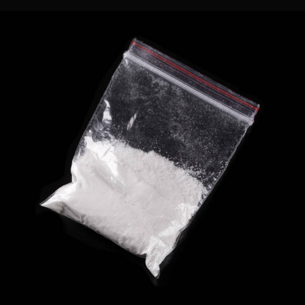 kokain in kunststoff-paket auf schwarzem hintergrund - sachet stock-fotos und bilder