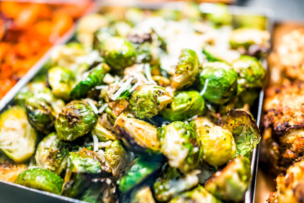 Macro closeup of roasted green brussels sprouts cabbage in tray on display in buffet, catering, deli, store, shop grocery market fresh, cheese stock photo
