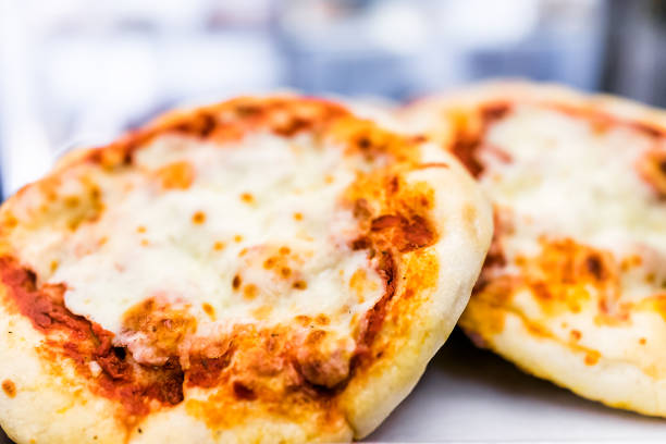 Macro closeup of two small mini pizza round circle plain with tomato sauce, melted mozzarella cheese