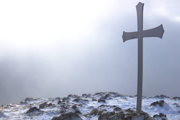 Two wooden crosses in cemetery covered in falling snow