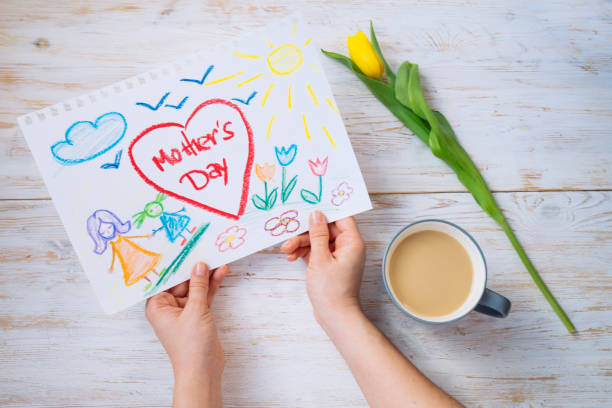istock mother look on kid picture with mother day congratulation while drink coffee. overhead view 931957454
