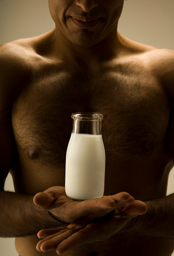 A muscular man balancing a bottle of milk on his palms