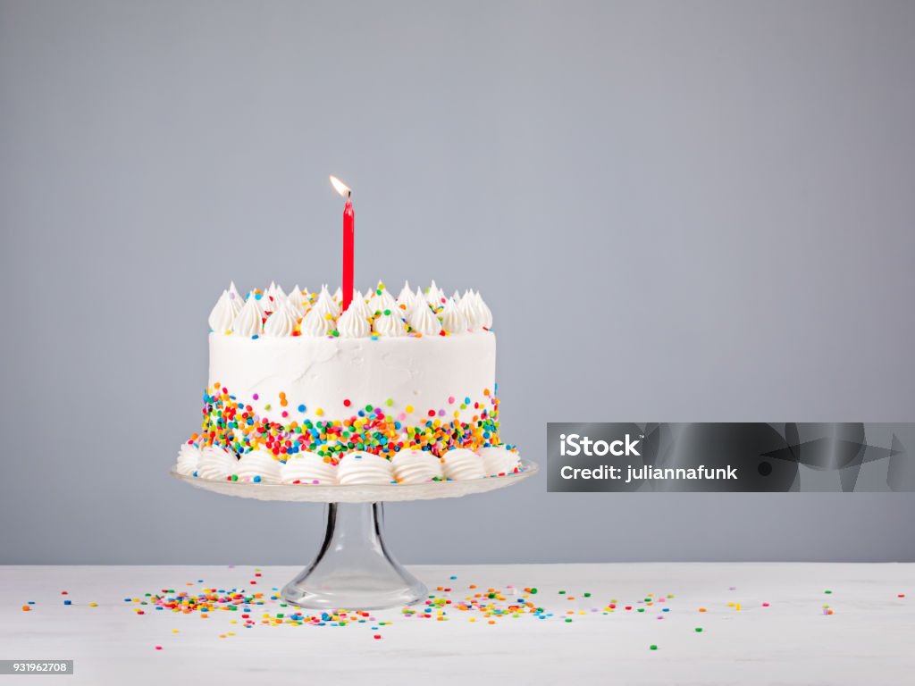 Birthday Cake with Red Candle White Birthday cake with colorful Sprinkles and red candle over a gray background. Birthday Cake Stock Photo