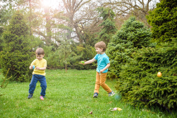 istock Kids on Easter egg hunt in blooming spring garden. Children searching for colorful eggs in flower meadow. Toddler boy and his brother friend kid  play outdoors 931968766