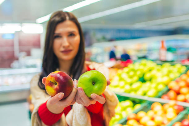 Young girl buys apple in grocery store.