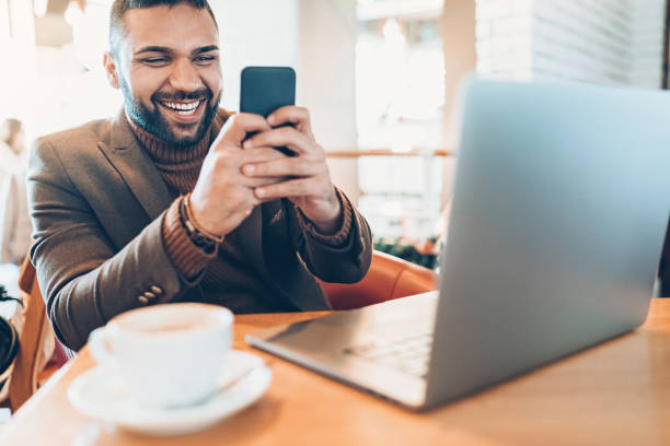 istock Handsome businessman with smart phone and laptop sitting in cafe 931990366