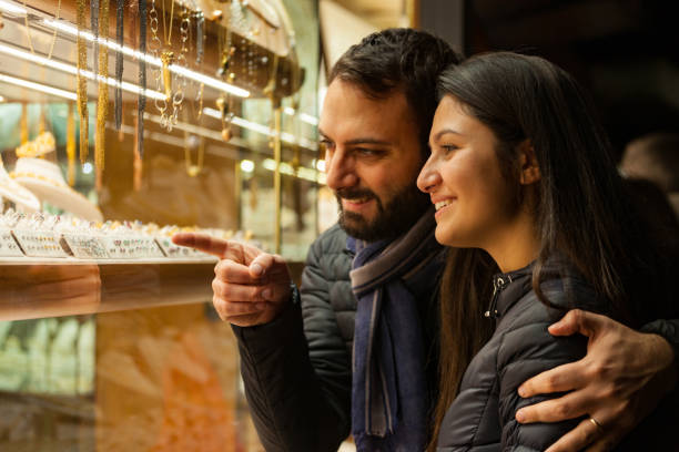 istock Smiling Couple Looking At Jewelry In Store Through Window 932006888