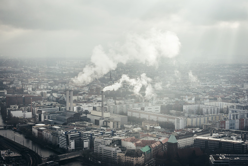 Factory in the center of Berlin city with smoke going from chimneys. Aerial view of industrial city