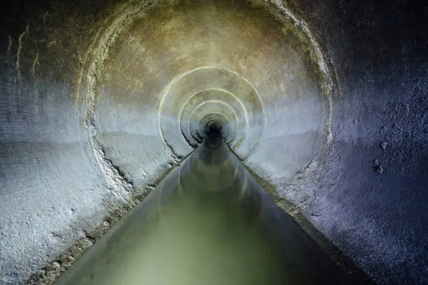 Photo of Dirty urban sewage flowing throw round sewer tunnel pipe