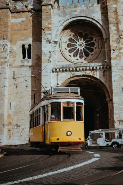 Quaint yellow tram passes directly in front of the Se Cathedral in Lisbon. Lisboa Lissabon.