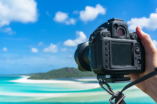 Person taking photo of tropical beach with DSLR camera. Tropical holiday background