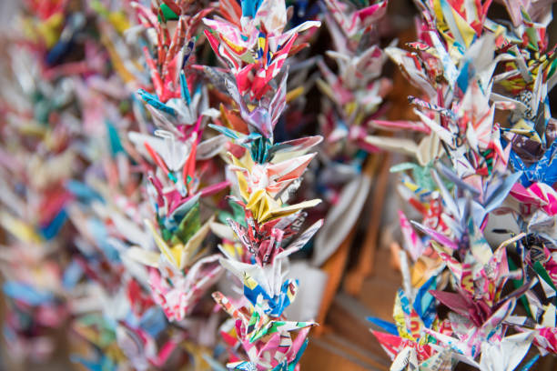 Red origami crane ( tsuru ) photographed on white base with white wall as background.