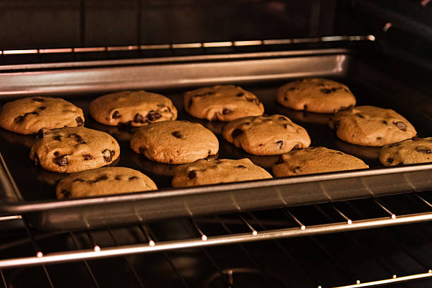 A dozen cookies baking in the oven Chocolate chip cookies baking on the oven rack. baking sheet stock pictures, royalty-free photos & images