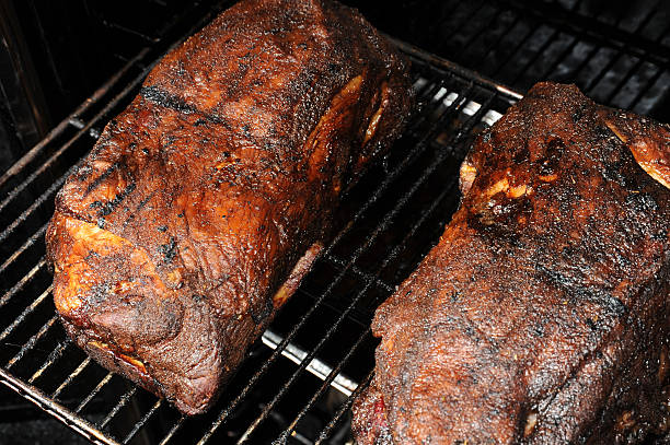 Smoked Pulled Pork Barbecue Two pork shoulders - also known as "Boston Butts" - shown after being smoked for 20 hours in a meat smoker. This meat will be pulled from the bones and used to make pulled pork sandwiches. Focus is on the left pork shoulder. barbecue pork stock pictures, royalty-free photos & images