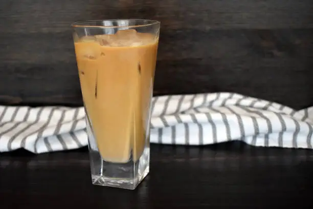 A tall glass of iced coffee with a cloth napkin in the background