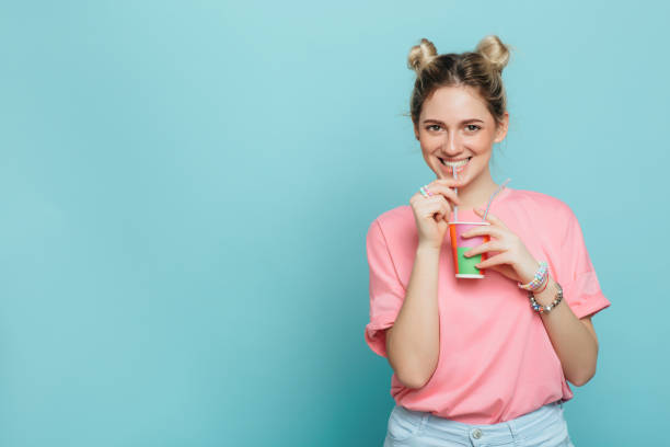 istock young woman holding paper cup and drinking 932050458