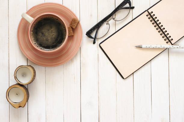 istock Notepad with pen, coffee, glasses and candles on desk 932056138
