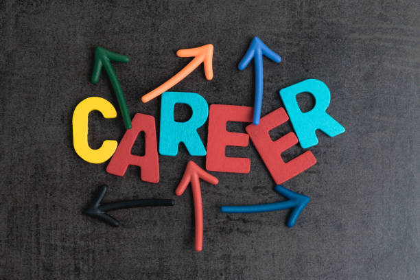 istock Uncertain career path opportunities concept by colorful wooden alphabets CAREER with multi directional arrow on dark black cement wall 932056534